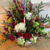 Large mixed flower arrangement with red roses, white hydrangea, and purple accents in a white basket