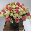 Pink and white roses arranged in a glass vase on a wooden table