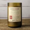 Olive-green glass jar candle with Unwined Candle Co. label on a rustic wooden surface