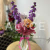 Bouquet of purple, pink, and orange flowers in a ribbed glass vase