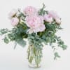 Soft blush peonies clustered in a clear glass vase make an effortlessly
