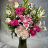 Pink lilies, roses, and carnations in a glass vase