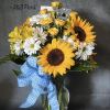 Bouquet of sunflowers, white daisies, and yellow roses in a glass vase with a blue ribbon