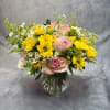Pink roses and yellow daisies in a clear glass vase