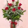 Red roses arranged in a glass pitcher with baby's breath and greenery
