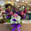Bouquet of pink roses, blue hydrangeas, and purple flowers in a glass vase