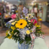 This colorful arrangement is designed in a ceramic blue daisy pitcher with