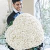 Man holding a large round bouquet of white roses