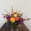 Mixed bouquet in a glass vase with yellow-orange roses and purple flowers