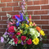 A COLORFUL ARRANGEMENT OF FRESH FLOWERS IN A WICKER BASKET.  ACTUAL