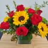 Red roses and yellow sunflowers in a square glass vase
