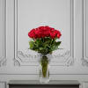 Red roses in a clear glass vase with a striped ribbon