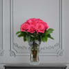 Pink roses arranged in a clear glass vase with a striped ribbon