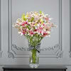 Pink and white lilies in a clear glass vase with a striped ribbon