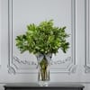 Green leafy arrangement in a clear glass vase with a striped ribbon