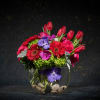 Bright mixed bouquet in a round glass vase with stones
