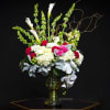 Tall floral arrangement in a glass vase with white calla lilies and orchids