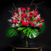 Large bouquet of red roses in a glass vase with tropical leaves