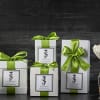 Gift boxes with green ribbons, a candle, and white flowers in a vase