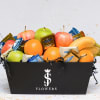 Fruit and chocolate gift box with apples, oranges, bananas, and wrapped candies