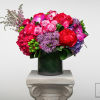 Bright mixed bouquet in a dark vase on a pedestal