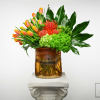 Orange tulips and red tropical flowers in an amber glass vase