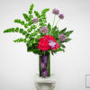 Tall modern arrangement with green bells of Ireland, pink hydrangea and purple orchids in a glass vase