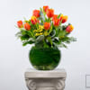 Orange and yellow tulips in a green glass vase