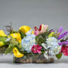 Colorful mixed flower arrangement in a low glass vase