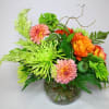 Bright mixed bouquet in a glass vase with orange, pink, and green blooms