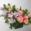 Pink roses and lavender orchids in a square glass vase
