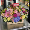Mixed bouquet in a wooden box with pink, yellow, purple, and blue flowers