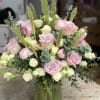 Pink and white roses arranged in a green glass vase
