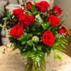 Red roses arranged in a clear glass vase with greenery