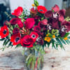 Bouquet of red roses and dark orchids in a glass vase