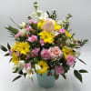 A cheerful blend of yellow daisies, soft peach roses, light pink mini