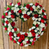 Heart-shaped wreath of red roses and white daisies on a stand