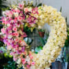 Heart-shaped floral arrangement of pink and cream roses with orchids