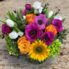 Colorful bouquet with sunflowers, roses, tulips, and white blooms in a glass vase