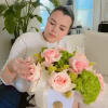 Woman holding a bouquet of pink roses and green hydrangeas in a white box