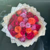 Bouquet of pink, orange, and lavender roses wrapped in patterned paper