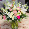 Mixed bouquet of pink, white, and peach flowers in a glass vase