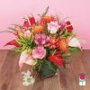 Tropical arrangement with pink roses, orchids, red anthuriums and orange blooms in a glass cube vase