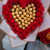Heart-shaped bouquet of red roses with gold-wrapped chocolates in the center