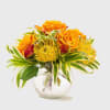 Orange roses and yellow flowers in a clear glass vase