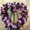 Heart-shaped floral wreath on an easel with purple and pink flowers