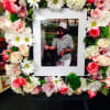 Flower wreath around a framed photo with pink roses and white daisies