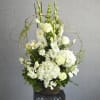 White floral arrangement in a wicker basket with tall stems and curly branches