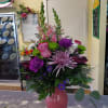 A glass vase arrangement filled with assorted seasonal flowers in shades of