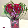 Red roses and pink filler flowers in a red glass vase
